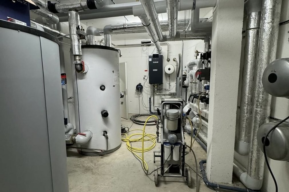 Heizungsraum mit Heizung und isolierten Rohren an der Decke