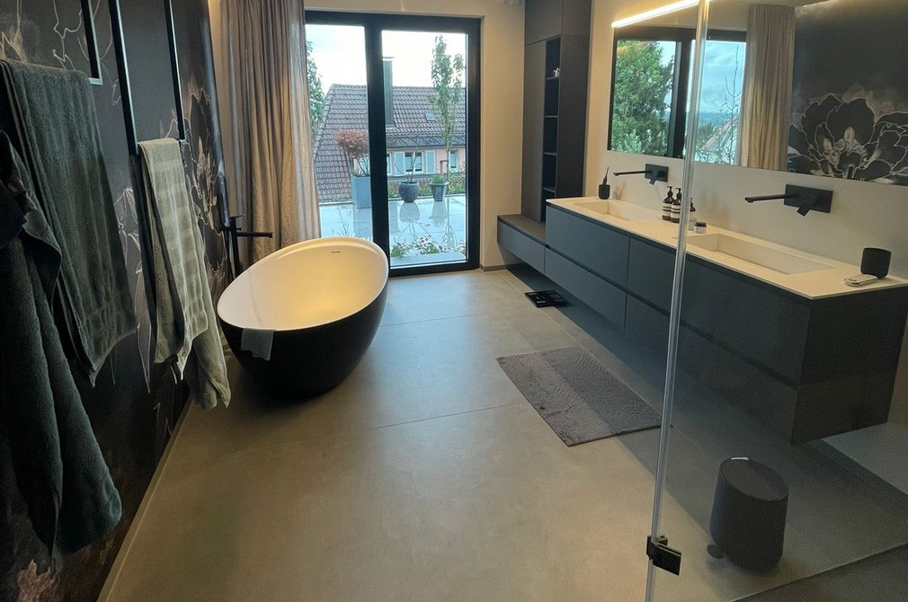 Ein modernes Badezimmer mit dunklen Wänden und gläserner Dusche