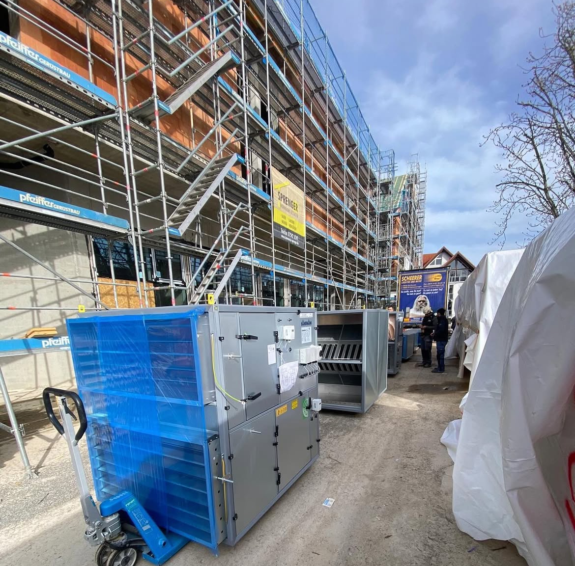 Foto einer Großbaustelle mit Sanitärenanlagen vor dem Gerüst des Hauses